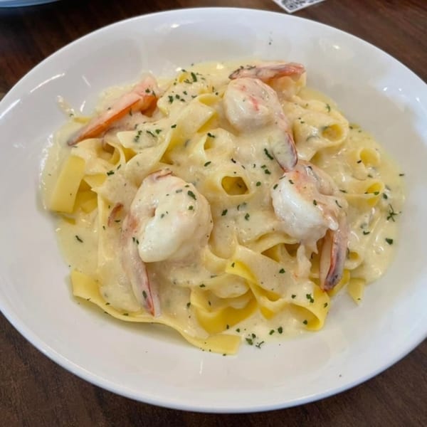 Creamy shrimp fettuccine pasta with parsley flakes in a white bowl at Villa Vinci.