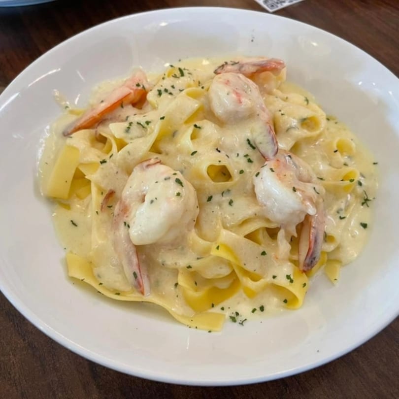 Creamy shrimp fettuccine pasta with parsley flakes in a white bowl at Villa Vinci.